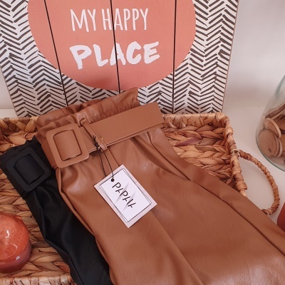 Saia de pele castanha e preta com cinto e etiqueta PRYK em cesto de fibras, cartaz MY HAPPY PLACE ao fundo