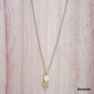 Colar dourado com pendente de ananás sobre madeira clara