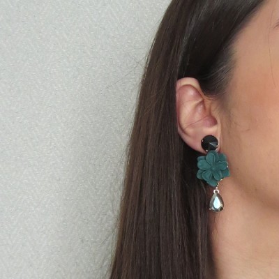 Brinco pendente com flor verde azulado e gota transparente numa orelha
