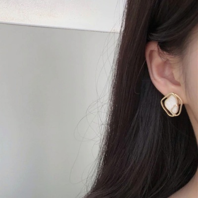 Brinco dourado com pedra branca em orelha de mulher com cabelo castanho