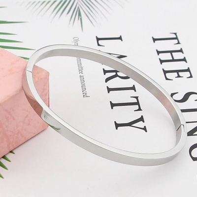 Pulseira prateada lisa e brilhante sobre papel com texto e bloco rosa