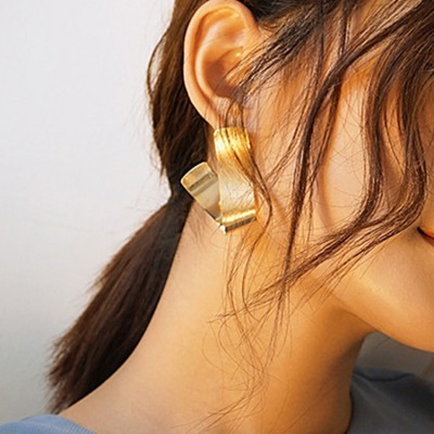 Brincos dourados modernos usados por mulher com cabelo castanho preso
