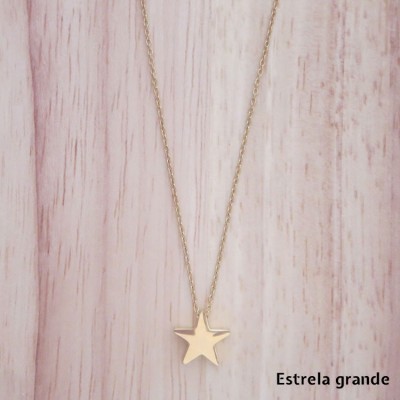 Colar dourado com estrela grande em fundo de madeira clara