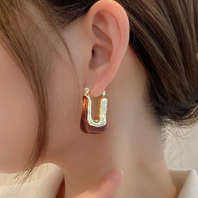 Brincos dourados em forma de U com textura irregular