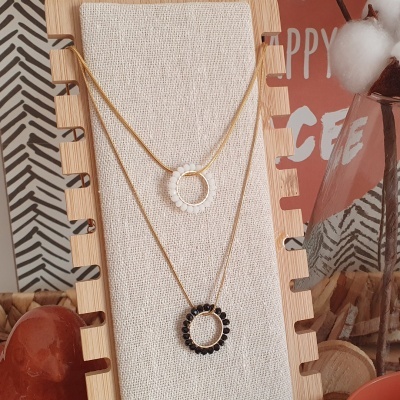 Dois colares dourados com pendentes circulares em suporte de tecido bege