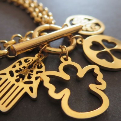 Pulseira com pendentes dourados de mão de Fátima, anjo e trevo