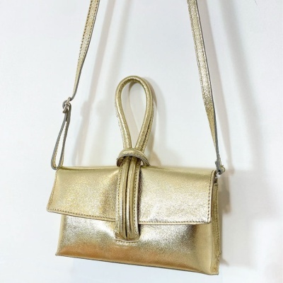 Mala de ombro pequena dourada com fecho em nó pendurada