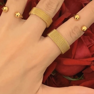 Mãos com anéis e braceletes dourados e pétalas de rosas vermelhas ao fundo