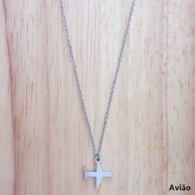 Colar prateado com pendente em forma de avião sobre madeira clara