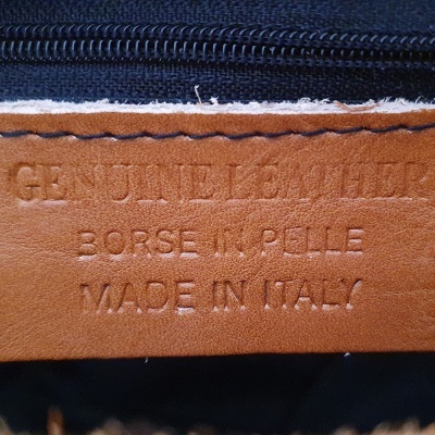 Etiqueta de couro castanho com texto gravado em tecido escuro e fecho preto