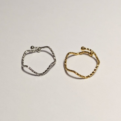 Dois anéis finos prateado e dourado com textura facetada sobre fundo claro