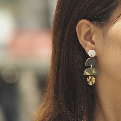 Brinco pendente com formas geométricas e cores branco, cinzento, verde e dourado