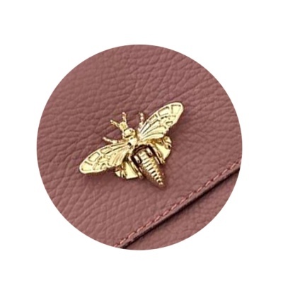 Fecho em forma de abelha dourada em bolsa de pele sintética rosa escura com textura granada