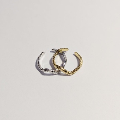 Dois anéis abertos entrelaçados, um dourado e outro prateado, com textura irregular