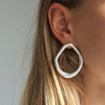 Brinco prateado de metal com forma irregular na orelha