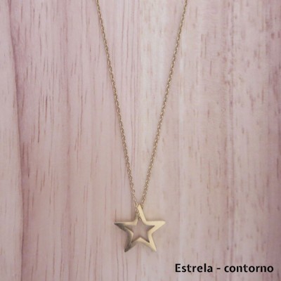 Colar dourado com pendente estrela vazada e fundo madeira clara
