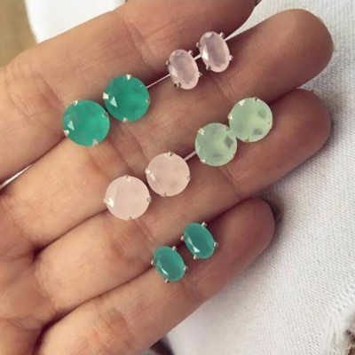 Mão segurando brincos de pedras facetadas verde, rosa e verde-água