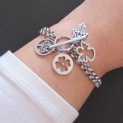 Pulseira prateada com três pendentes em pulso com manga branca