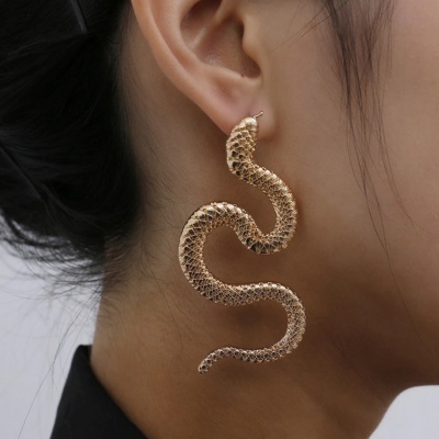 Brinco dourado em forma de serpente na orelha de uma pessoa