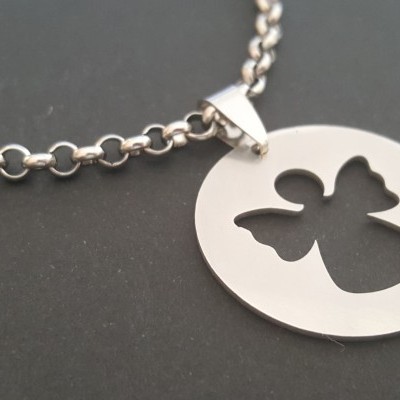 Colar prateado com pendente circular de anjo recortado sobre fundo preto