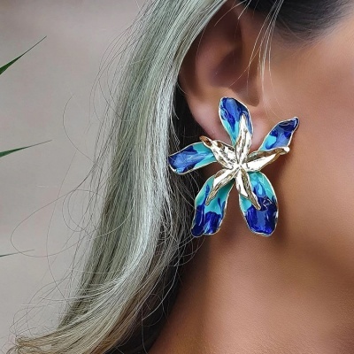 Brinco em forma de flor azul e prateada numa orelha feminina