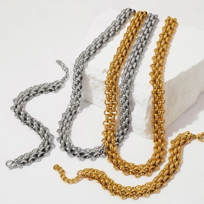 Colares metálicos dourados e prateados com elos entrelaçados sobre superfície branca