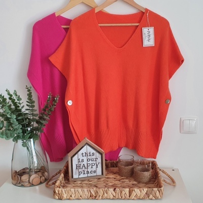 Duas camisolas coloridas penduradas e cesto decorativo com vasos e objeto em forma de casa