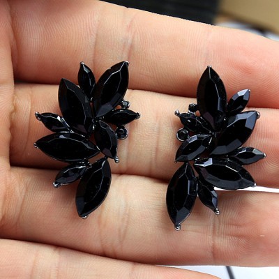 Brincos pretos com pedras facetadas em mãos