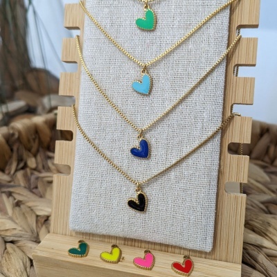 Colares dourados com pendentes de coração coloridos em suporte de madeira