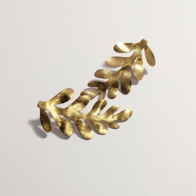 Brincos dourados em metal com design de ramos de folhas sobre fundo branco