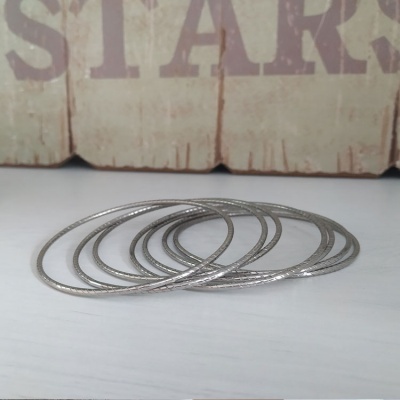 Conjunto de cinco pulseiras finas prateadas com textura sobre superfície branca