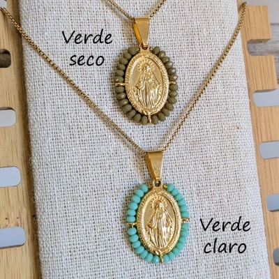 Dois colares com pendentes dourados e pedras verdes em fundo bege e madeira