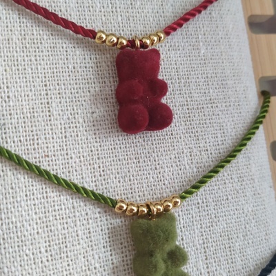 Colares com ursinhos felpudos e contas douradas sobre tecido cru