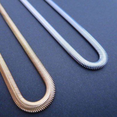 Colares dourado e prateado com textura de elos pequenos sobre fundo escuro