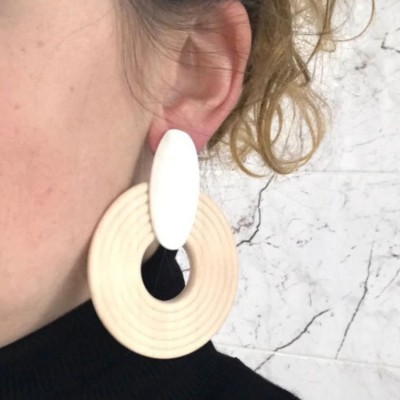 Brinco grande em argola clara com base oval branca na orelha de pessoa