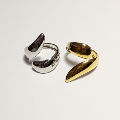 Anéis metálicos curvos dourado e prata sobre fundo branco