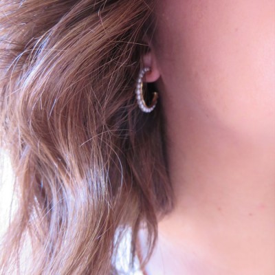 Brinco de argola com pérolas brancas numa orelha