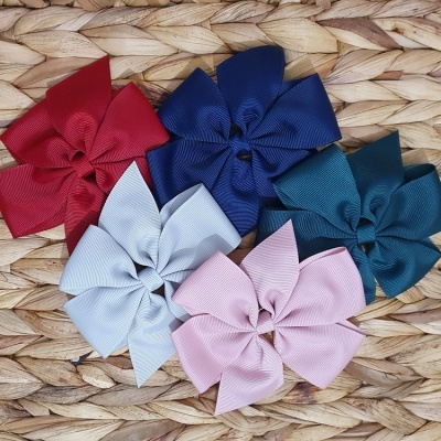 Cinco laços grandes de tecido coloridos sobre fundo de fibra natural