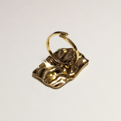 Anel dourado com base ondulada e textura metálica em fundo branco