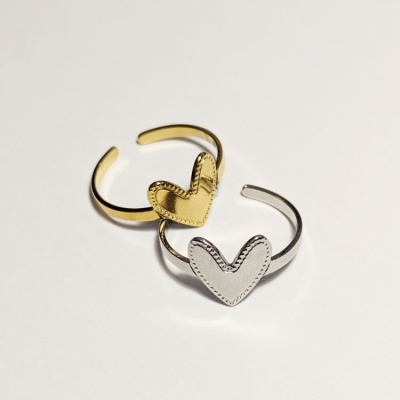 Dois anéis metálicos com corações, um dourado e outro prateado, sobre fundo branco