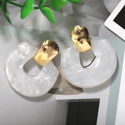 Brincos circulares em resina branca marmoreada com detalhes metálicos dourados