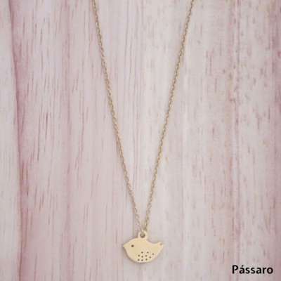 Colar com pendente dourado em forma de pássaro sobre madeira clara