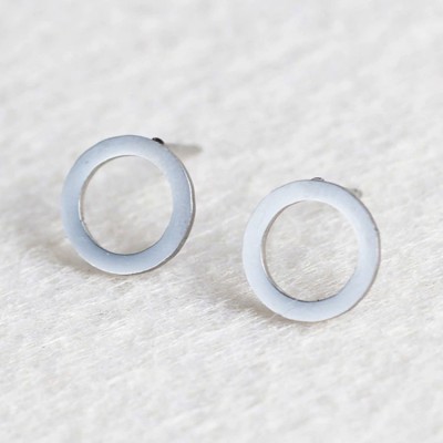 Brincos circulares brancos translúcidos sobre tecido claro