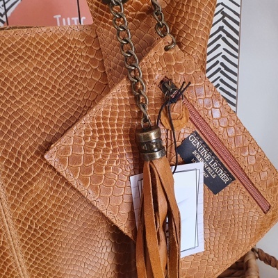 Bolsas de pele castanha com textura de escamas e pingente de couro com corrente