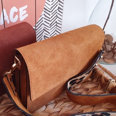 Mala castanha em camurça com alça animal print sobre superfície trançada