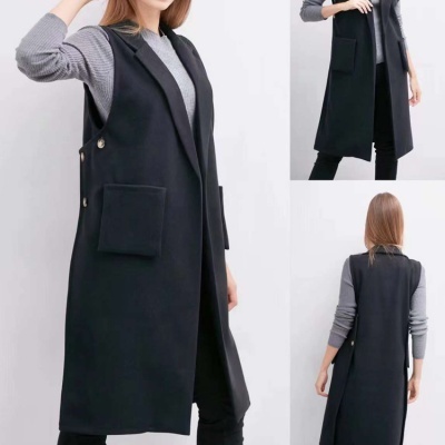 Colete preto comprido com botões laterais e bolso frontal sobre camisola cinza