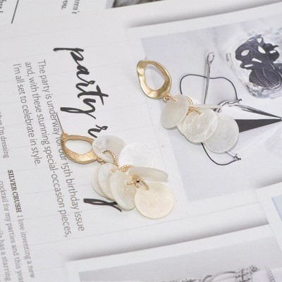 Brincos dourados e translúcidos sobre páginas de revista com texto e imagens.