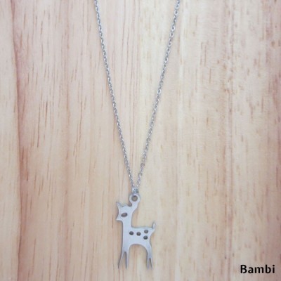 Colar com pendente de veado prateado sobre fundo de madeira
