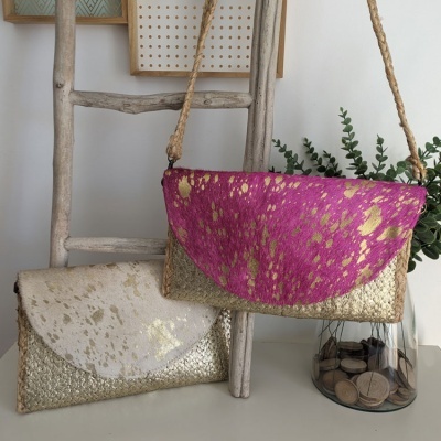 Duas bolsas de mão metalizadas penduradas numa escada de madeira, com vaso de moedas ao lado