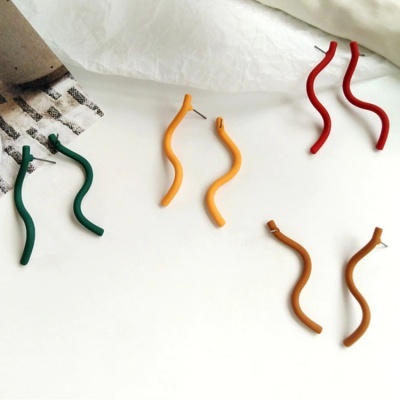 Quatro pares de brincos ondulados em várias cores sobre superfície branca